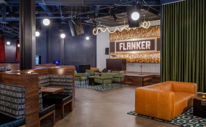 Modern lounge space with cozy booths, velvet seating, and illuminated Flanker sign