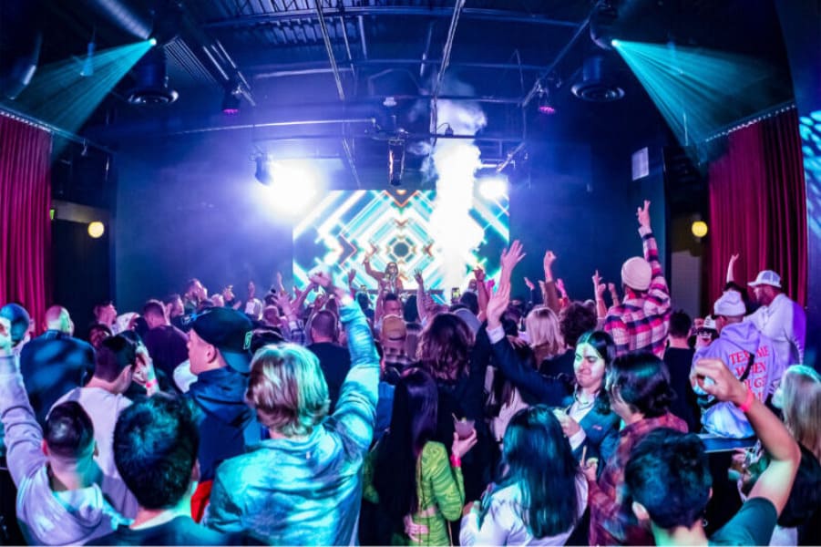 Crowd dancing at a nightclub with DJ lights and stage effects