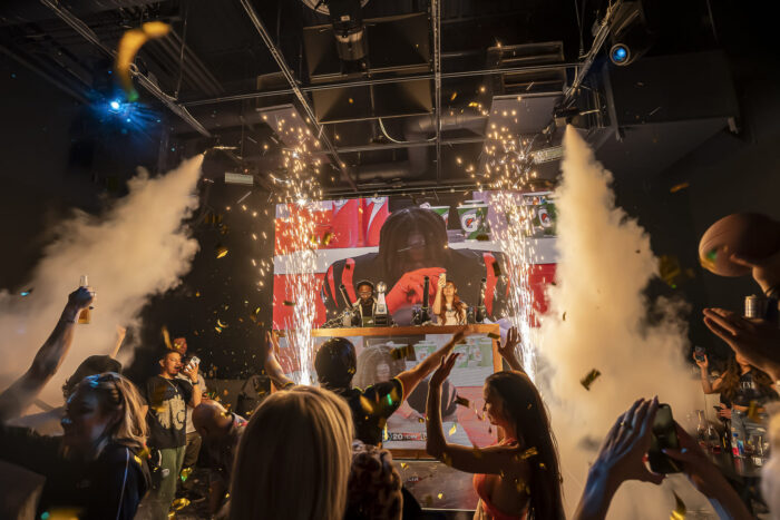 Image pop-up Guests celebrate inside a lively sports bar with confetti, sparklers, smoke effects, and large video screens.
