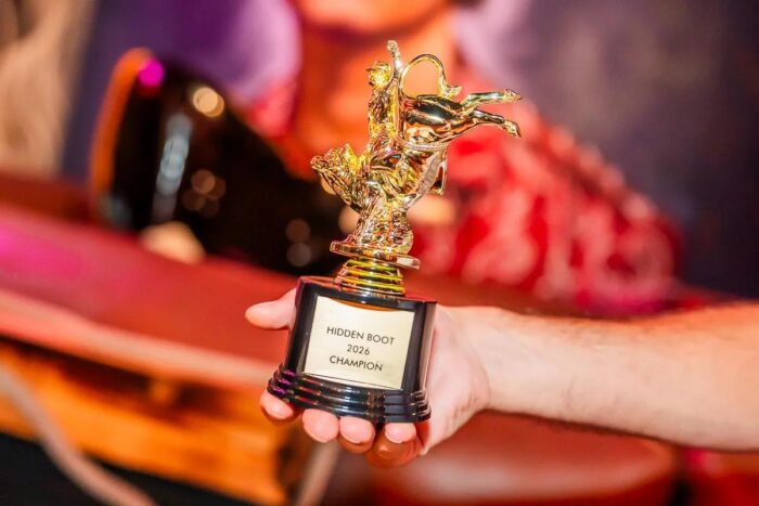 Image pop-up Person holding a gold trophy labeled “Hidden Boot 2026 Champion.”